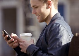 A young man sitting on a bench, using his mobile phone