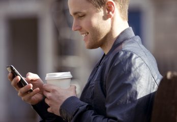 A young man sitting on a bench, using his mobile phone