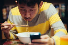 Japanese man eating noodles while reading