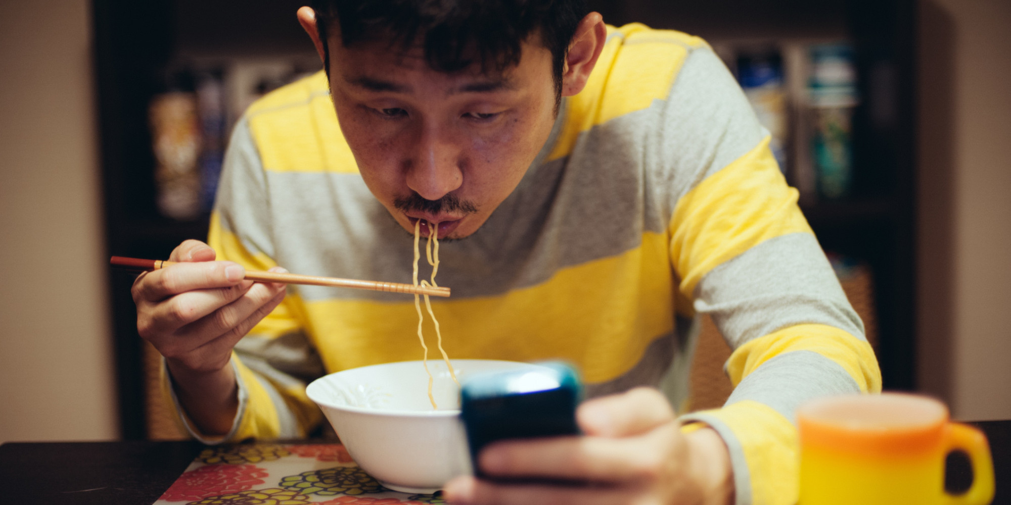 Japanese man eating noodles while reading